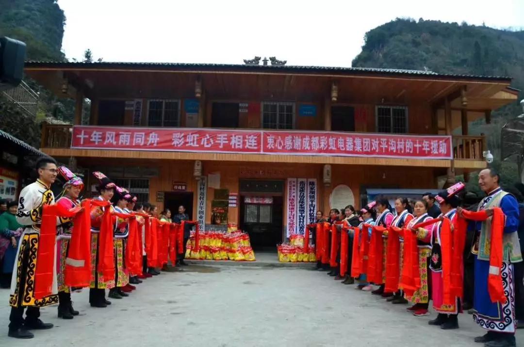懷感恩之心，平溝村村民手持羌紅在彩虹公司援建的平溝村便民服務(wù)樓前熱情等待彩虹親人們的到來